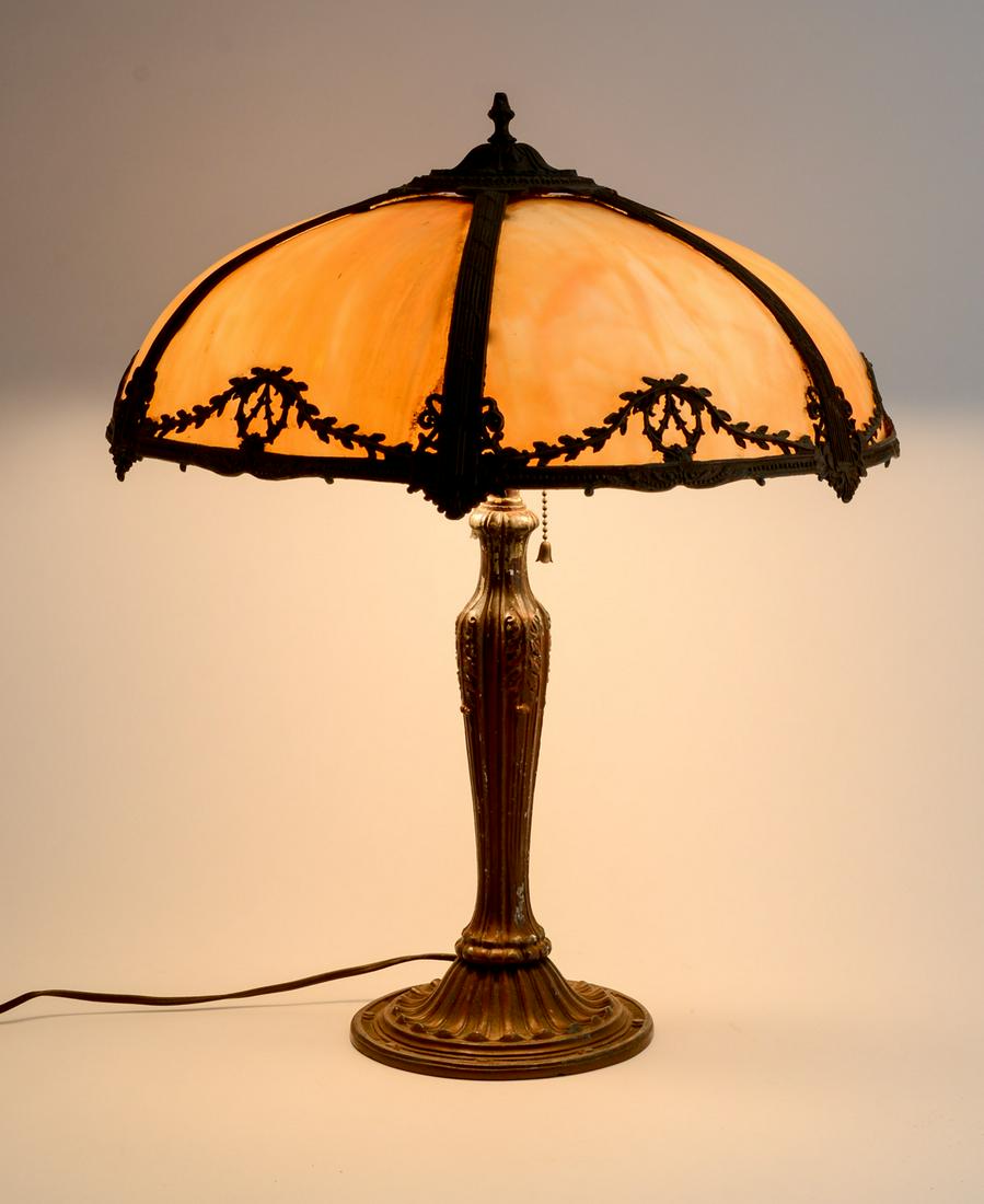 Slag Glass Panel Lamp: Antique Painted Cast Metal and Caramel Slag Glass Table Lamp. Unsigned. no cracks or breaks on the glass panels. Paint loss on shade and areas of base. some bending to overlay on shade, and minor loss