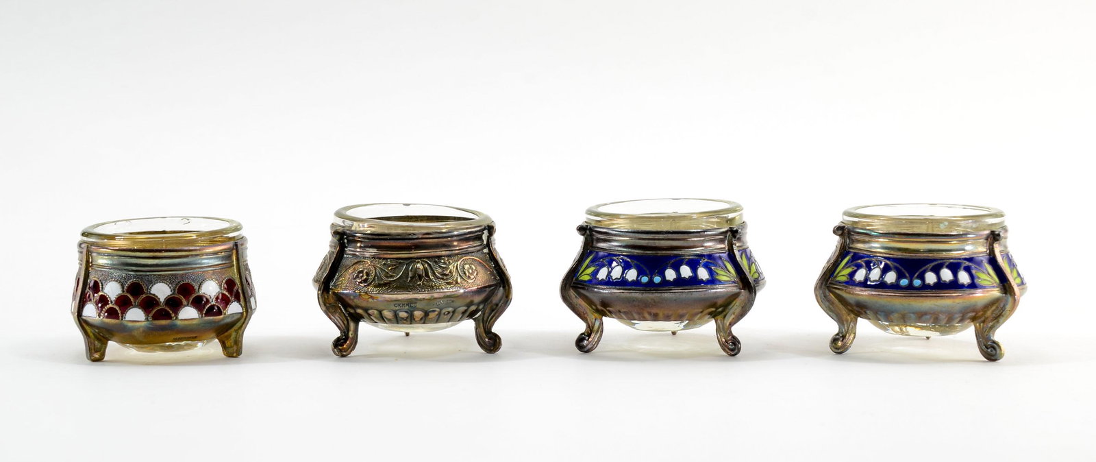4 Russian Champleve / Silver Plate Open Salts: Four Russian open salts. All marked 'Oiommet' and retain glass inserts. Including a pair of enameled Lily of the Valley, enameled fishscale in red and white, silver plate scrolling floral pattern. 1 5