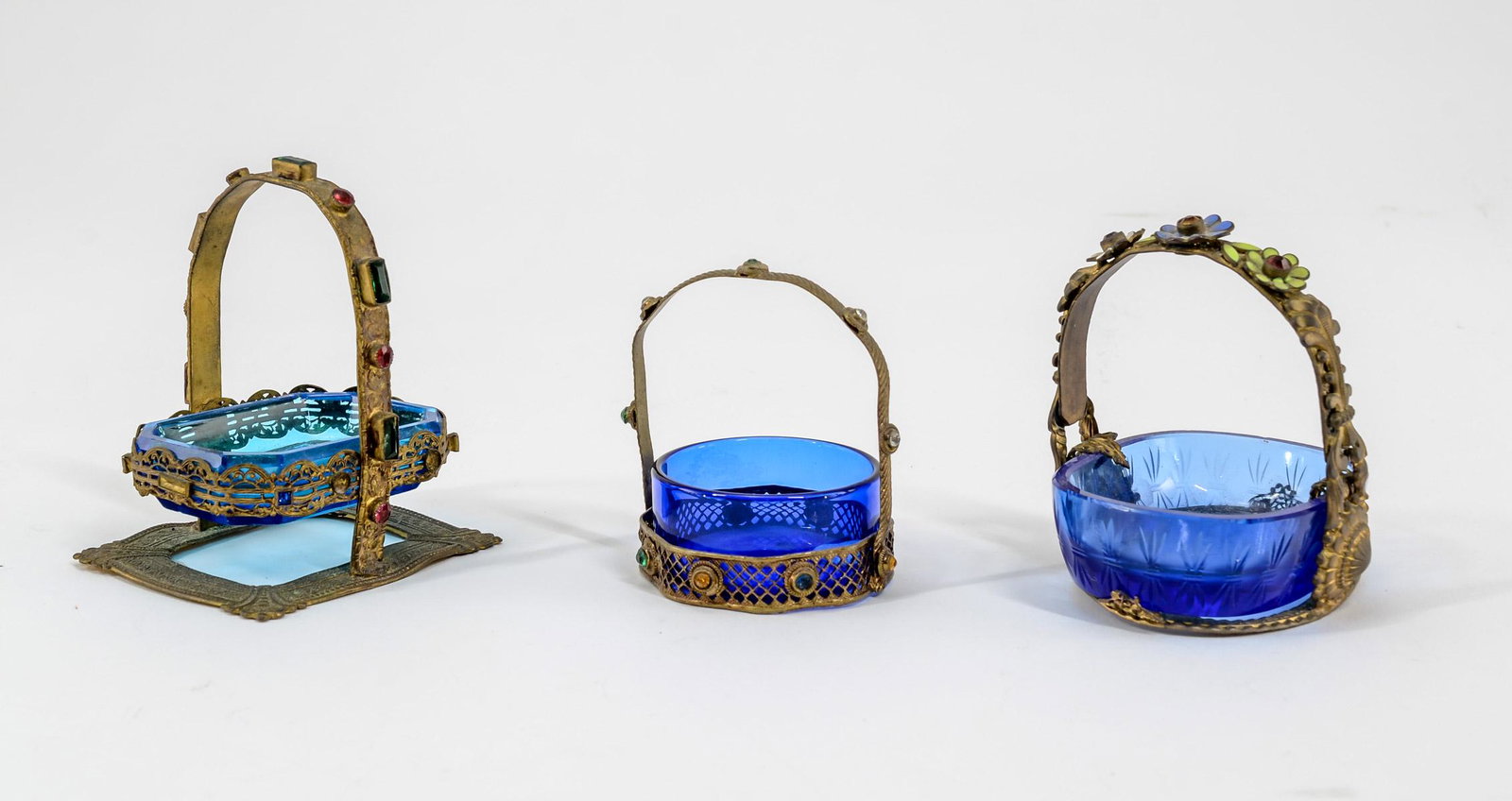 3 Intaglio Glass open salts in Frames: Three Intaglio cut glass open salts in frames. Including: 1 - Gilt metal basket form frame with enameled flowers in handle. Cobalt bowl with Classical scene, 3" high x 2 1/4" wide x 2 3/4" long. 2 - G