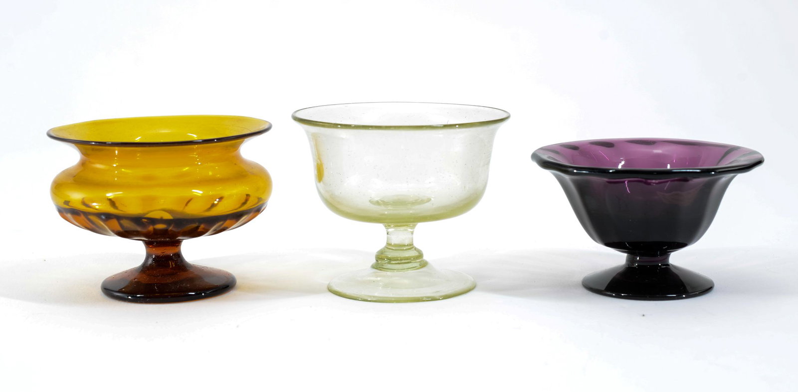 3 Blown Glass Pedestal Open Salts: Three blown glass pedestal open salts. Colors include: Amber, colorless and amethyst. 19th century. All in very good condition, each with pontil marks. Keywords: Salt Cellar, Salt Dip, New England, Am