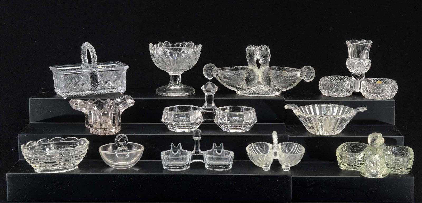 12 Clear Glass Open Double Salts: Twelve clear glass double open salts. Various patterns: Dog, chickens, basket, etc. All appear to be in good condition, not inspected individually. Keywords: Salt Cellar, Salt Dip, Figural, Victorian