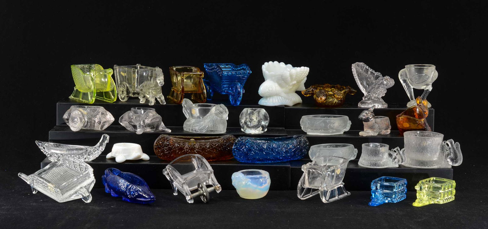 28 Glass figural Open Salts: Twenty eight glass figural open salts, master salts / candy containers. Various colors. Figures include: Canoe, frog, wheel barrow, turtles, birds, butterfly, sleighs, log, rabbit, squirrel on tree, d