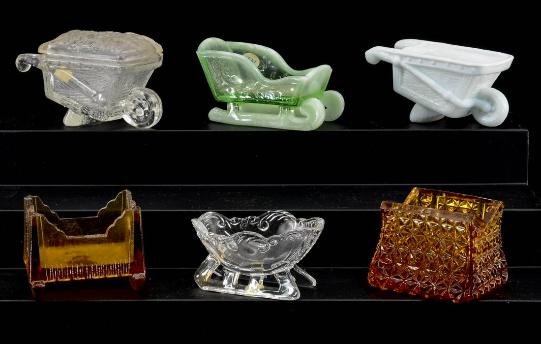 6 Figural Glass Open Salt / Candy Containers: Six figural glass open salts / candy containers. Including: Opalescent / green sleigh, repro amber cradle, milk glass wheel barrow, clear glass wheel barrow with cover, clear glass sleigh, amber carpe