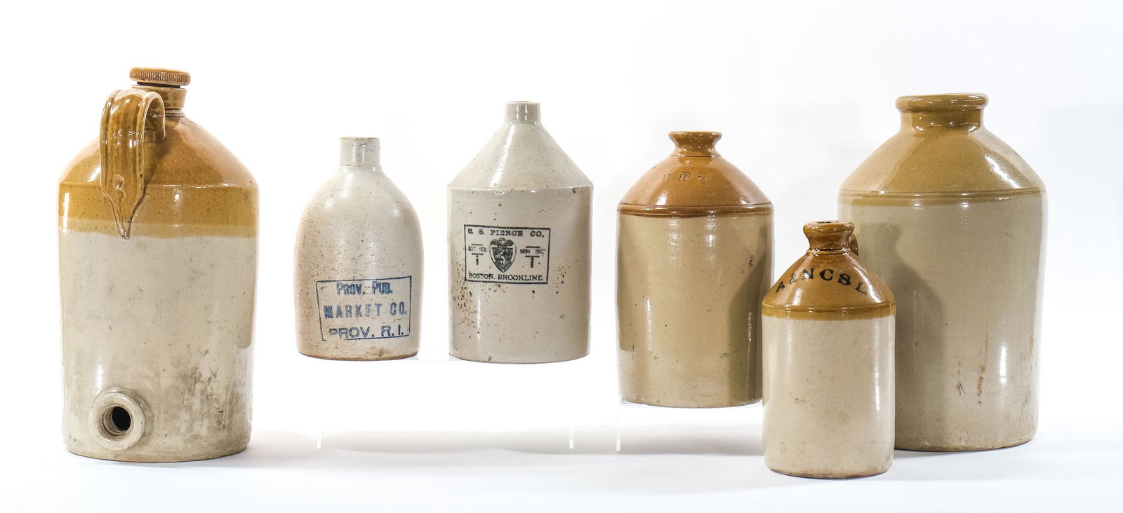 Six Stoneware jugs: Boston, Rhode Island, etc.: Includes a large 2-gallon "pig" bottle with one of two threaded screw caps, marked "Price Bristol" Large mouth jug is unmarked, One "S.R.D." one "1/2 X A&NCSL" an S.S. Pierce Co, Boston Brookline, and