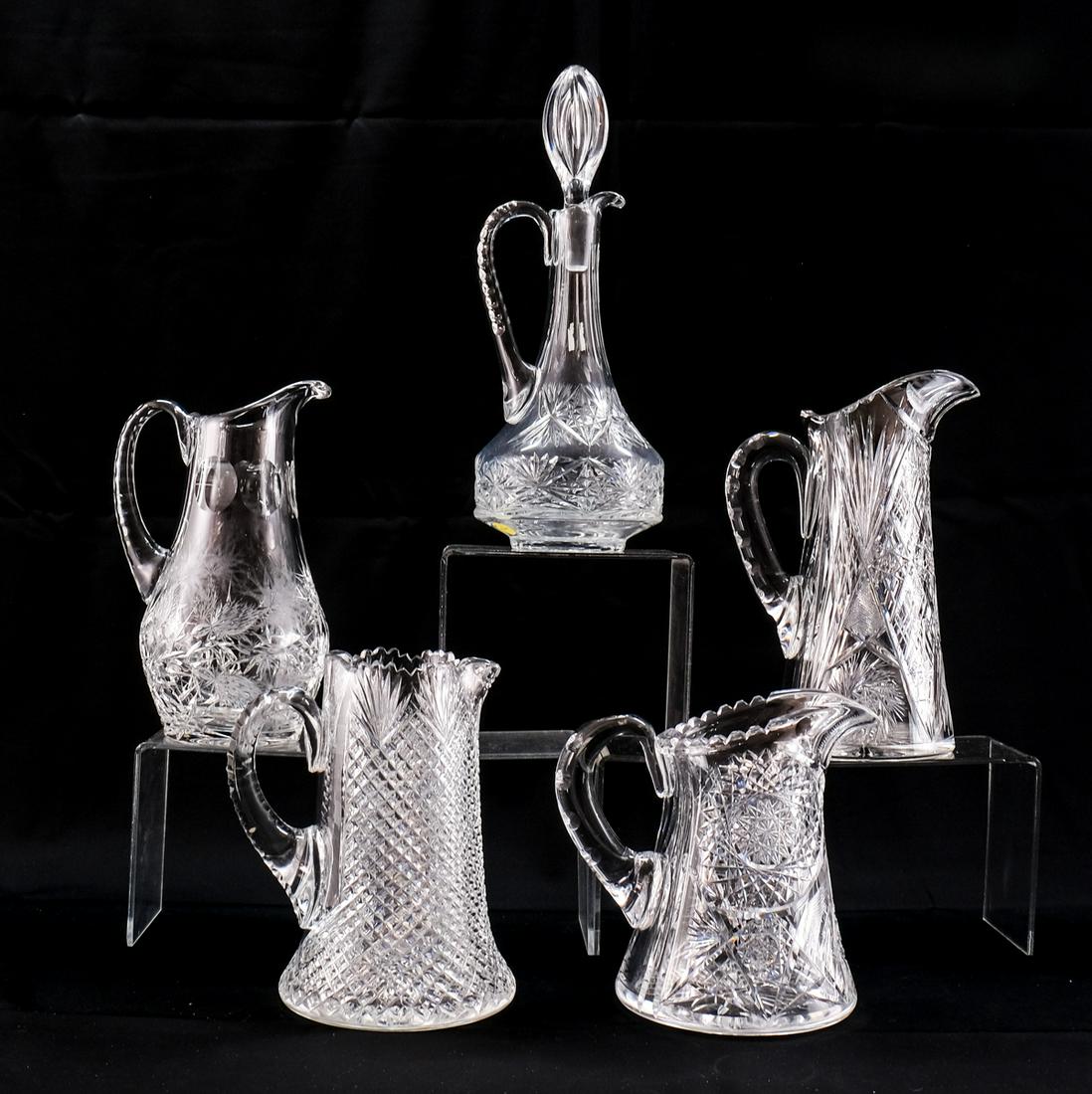 5 pcs American Brilliant Cut Glass: 4 pitchers/jugs and 1 decanter or claret with stopper. 8 1/2" tall and 8 1/2" from spout to handle pitcher/jug unsigned with star and hatch pattern, heavy shelf wear . A 11 1/4" tall and 8" from spout