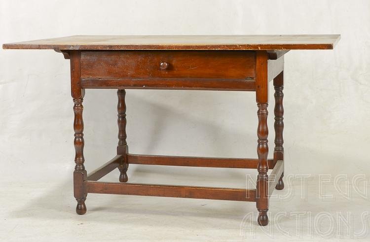 Walnut Tavern Table: Tavern table. Walnut. Top is pine (not original). Origin unknown. One drawer with single wooden pull. Baluster turned legs with stretcher base. Old refinish. Mid to late 18th century. 27 3/4 H x 50 W 