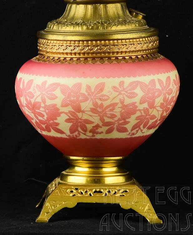 Mt. Washington Cameo Glass Kerosene Lamp: Mount Washington cameo cut satin finish pink and white glass electrified kerosene lamp. Good overall. Lamp sits on a brass four footed base. Rewiring this piece is recommended. 