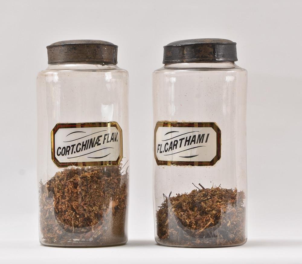 Two Early Glass Apothecary Jars: Hand Blown spun glass with hand decorated applied glass labels, each with original tin lids, each 13" Tall. Herb contents remain. 18th or 19th Century, excellent condition.