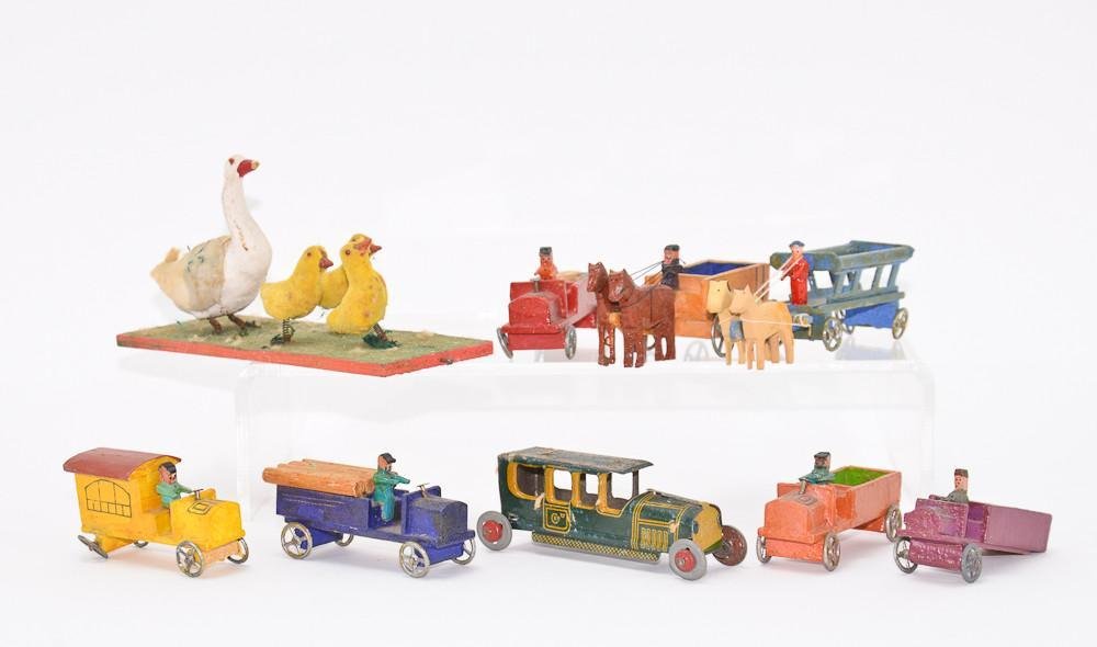 Group of German Miniature toys: One Metal car, and seven wooden wagons and trucks. One truck with missing axle, and one with axle separated. also includes a spring mounted group of geese. each toy stamped "GERMANY" each ap