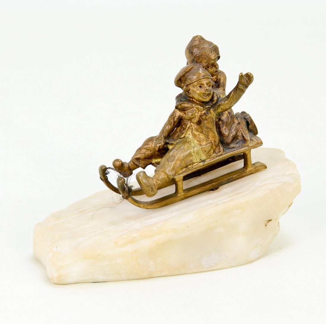 Bronze Figurine of Boys on Sled: Bronze figurine on white stone with patina in good condition, 4.5" x 5.5" signed on back. Circa 1900.