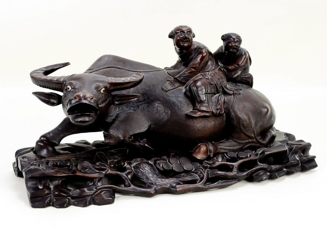 Chinese Carved Wood Water Buffalo w/Children: Finely carved water buffalo with children upon his back. Floral carved base. 8" x 18.5" x 10.5". Missing part of left horn and has some age cracks. Late 19th or Early 20th Century.
