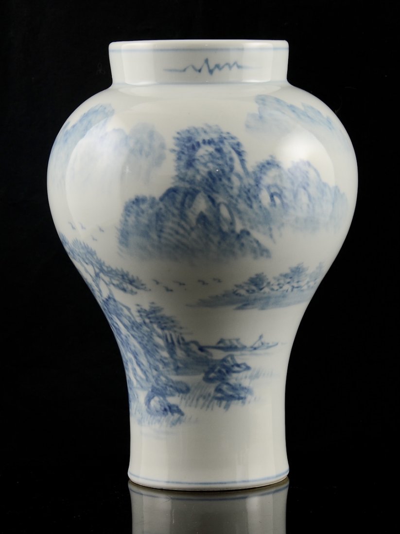 Korean Studio Porcelain Vase: White porcelain vase with a blue glaze rendering of mountains, trees, birds and an individual in a boat. Signed on the bottom. The vase is 13" high. In good condition with no cracks or marks and has n