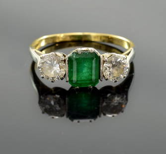 Ladies 18K Emerald and Diamond Ring: A center Emerald-cut Natural Emerald flanked by two Round Brilliant Diamonds. Hallmarked 18K and the makers mark S.H&Co. Likely Sackermann, Hessenberg & Co. Early 20th Century. The center Emerald is a