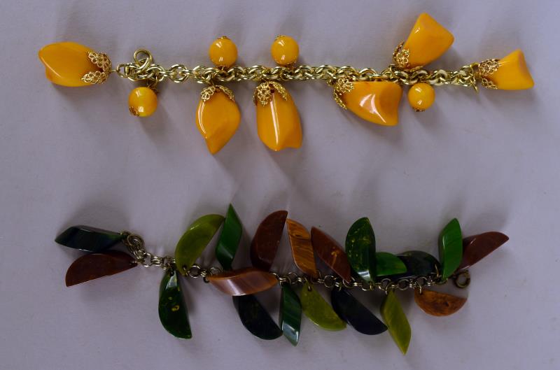 Two Bakelite Charm Bracelets: Consisting Of A Butterscotch Bakelite Bracelet And A Green And Brown Bakelite Bracelet. The Bracelets Measure 7" And 7.5" Long, The Charms Measure 1" Long. The Butterscotch Has A Replacement Clasp. No