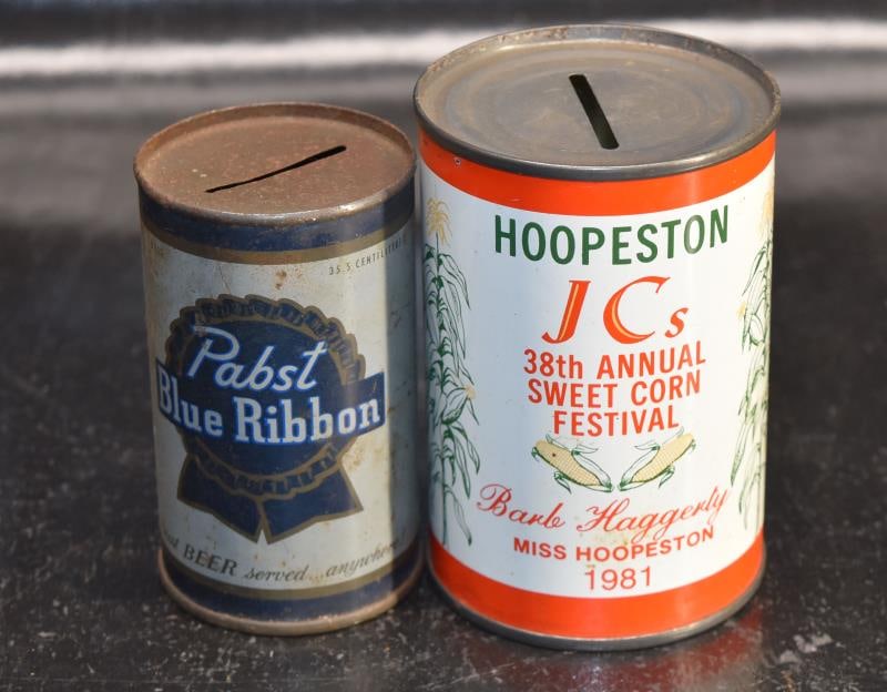 Two Metal Can Advertising Banks: Featuring A Pabst Blue Ribbon Bank, Measuring 3.5" Tall And 2.5" Across. Together With The 1981 Hoopeston Sweet Corn Festival Bank, Measuring 4" Tall And 2.75" Across.