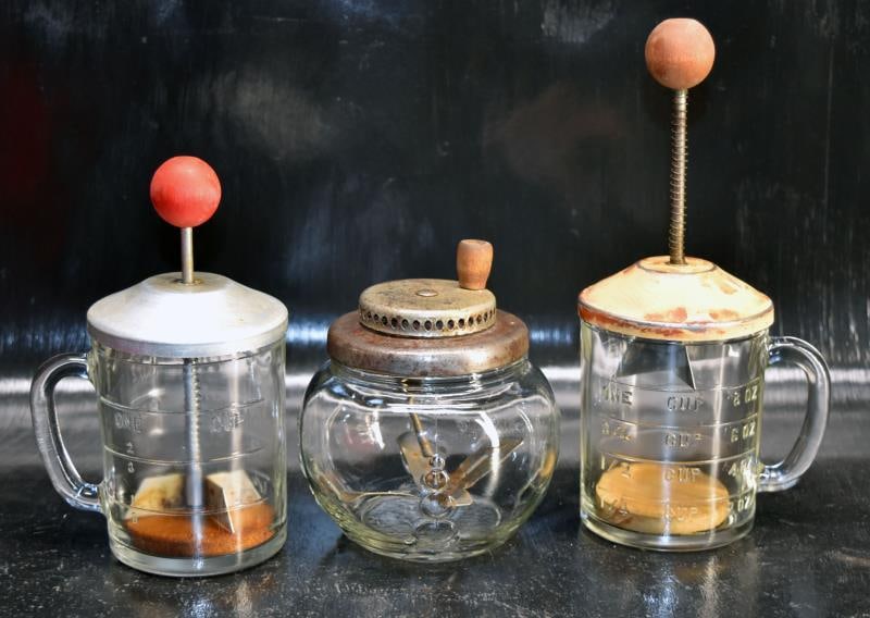 1930's Glass Jar Egg Beater: A 1930's Glass And Metal Manual Egg Beater, Measuring 5" Tall And 4" Across, No Chips Or Cracks. Together With Two Hazel Atlas One Cup Nut Choppers, Both With Wood Handles, No Chips Or Cracks.