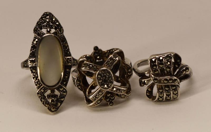 Three Sterling Silver & Marcasite Rings: Featuring Three Sterling Silver And Marcasite Rings, All Marked 925. The Marcasite And Mother Of Pearl Ring Is Size 6, The Knot Ring Is Size 6 And The Ribbon Ring Is Size 5.5.
