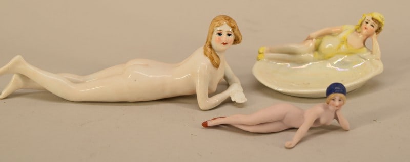 German Art Deco Porcelain Nude Figurines: Featuring And Unmarked Nude Woman Reclining On Her Stomach, Measuring 6" Long, In Good Condition. Together With A German Hertwig Bathing Beauty On An Oyster Shell Pin Or Ring Dish. Measuring 3 1/2" Lo