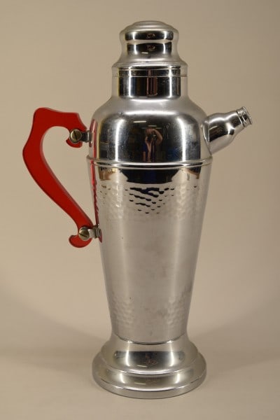 Art Deco Chrome Cocktail Shaker W/ Bakelite Handle: Featuring An Art Deco Chrome Cocktail Shaker, With A Red Bakelite Handle. The Music Box Plays For He's A Jolly Good Fellow When Picked Up. Good Condition, No Cracks Or Dents, No Hallmark, Needs A Good