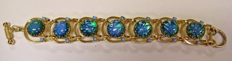 Contemporary Chain Link Green Bracelet: Consisting of seven iridescent green & blue glass links with a toggle clasp. No hallmarks, measuring 8" long and 1.25" wide.