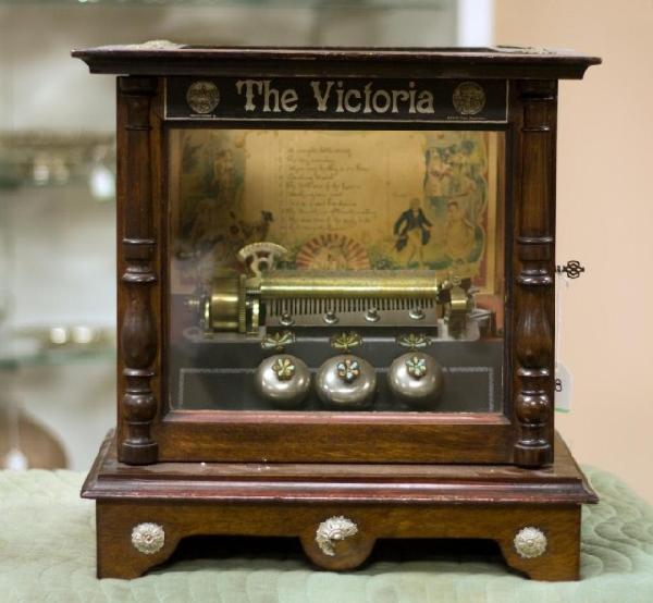 ANTIQUE SWISS WOODEN TABLE TOP MUSIC BOX: Antique Swiss table top music box made by B.H.A. in Ste. Croix, Switzerland. Called "The Victoria". Has ten songs written in English on a colorful song list depicting people and cherubs. Box has glass