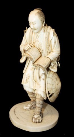 ORIENTAL IVORY FIGURE OF MAN HOLDING BOOK: Fabulous quality. Piece depicts a man walking while looking at a book. He is wearing sandals and has a hat on his side. He has a satchel with flowers on his back. Wonderful craftsmanship. The book has