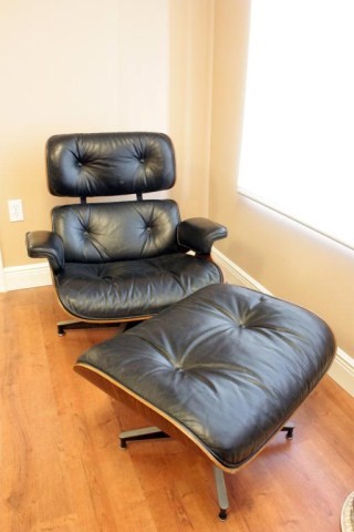 HERMAN MILLER LEATHER CHAIR w OTTOMAN: Black leather and section wooden back paneling. Chair has swivel base. Chair measures 33"" h X 33 1/4"" w X 31"" d. Ottoman measures 16 1/4"" h X 26"" w X 21 1/4"" d.