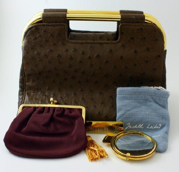 JUDITH LEIBER BROWN OSTRICH LEATHER PURSE: Fabulous Judith Leiber brown ostrich leather purse. Has gold hardware. Burgandy silk interior. Has detachable strap. Magnetic flap clasp. Includes Judith Leiber coin purse, mirror and comb. Measures 6