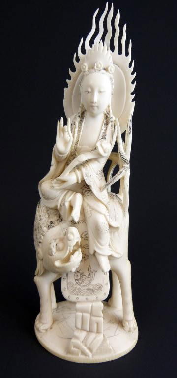 CHINESE IVORY HAND CARVED QUAN YEN ON FOO DOG: Depicts Quan Yen sitting on a foo dog's back. In her left hand is a scepter. Her right hand is forming a symbol. On her robe and saddle is a jumping fish, water, and clouds design. Measures 8 1/4" hei