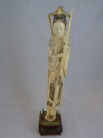ANTIQUE CHINESE IVORY FIGURE OF FEMALE WARRIOR: Depicts a woman in intricate layered robe with etched Phoenix, floral and cloud design. In each hand she is holding a sword. One to the front and the other to her back. Each sword has a tassle attache