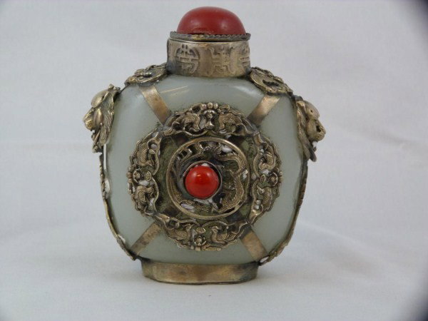 ANTIQUE CHINESE CELEDON JADE & SILVER SNUFF BOTTLE: Antique Chinese celedon jade snuff bottle. Has silver mounting depicting Phoenix birds, lion heads, and bats. 19th century. Signed to bottom. Measures 3 1/2" (8.8cm) height.