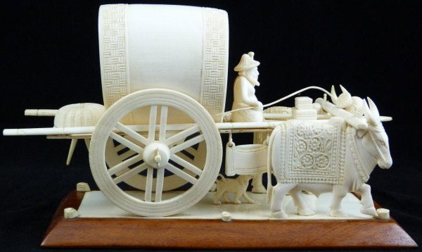 CHINESE IVORY OX WAGON GROUP CARVING: Beautifully carved Chinese ivory wagon group figure. Wagon is being pulled by oxen. The wagon frame is constructed of bamboo. The wagoneer's family is sitting inside the cart. A dog is following along