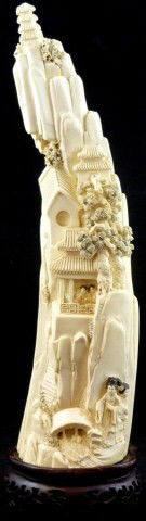 CHINESE IVORY MOUNTAIN VILLAGE CARVED SCENE: Chinese ivory carving of a mountain side scenic village. Scene depicts mountains, pagodas, streams, people and trees. Signature to reverse. Reverse also has etched landscape scenes. Measures 13 1/4" h