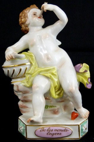 MEISSEN GERMAN PORCELAIN CHERUB FIGURE: A Meissen figure of Cupid seated in loosely draped robes, blowing with a straw into a heart (heart is broken and we do not have it), on a shaped triangular base with pink panels, one inscribed "Je Les