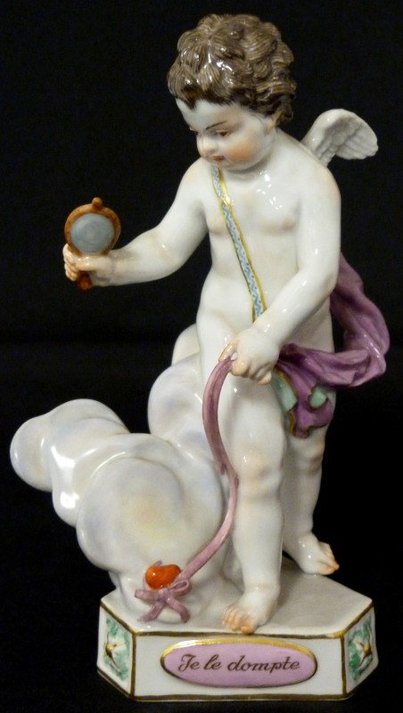MEISSEN GERMAN PORCELAIN CHERUB FIGURE F16: Meissen figure of a cherub standing and holding a heart on a ribbon leash with a mirror in his right hand. Has a triangular shaped base with pink panels, one inscribed "Je Les dompte". Blue crossed sw