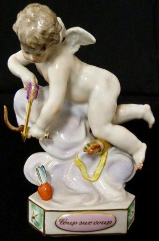 MEISSEN GERMAN PORCELAIN CHERUB FIGURE F10: Meissen figure of a cherub flying and aiming his arrow at a heart. Has a triangular shaped base with pink panels, one inscribed "Coup sur coup". Blue crossed swords mark to bottom. Impressed F10 and 1
