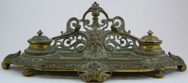 ANTIQUE FRENCH BRASS SCROLLED INKWELL: Very detailed French Brass inkwell. Has very detailed and reticulated floral scroll design throughout. Center has a pan face design which is used as the pen holder. Has four feet. Early 20th century. 