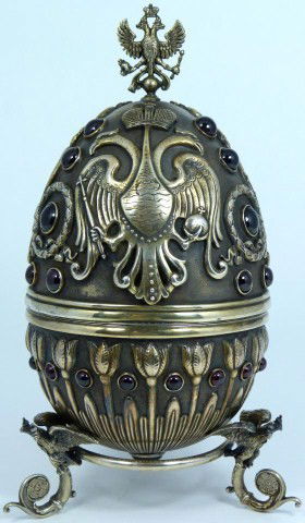 RUSSIAN SILVER JEWELED DOUBLE EAGLE EGG: Finely crafted Russian silver egg with raised Russian double eagle, wreath and floral design throughout. Has double eagle finial mounted to top. Has 32 set Cabochon garnets to exterior. Holds Imperial