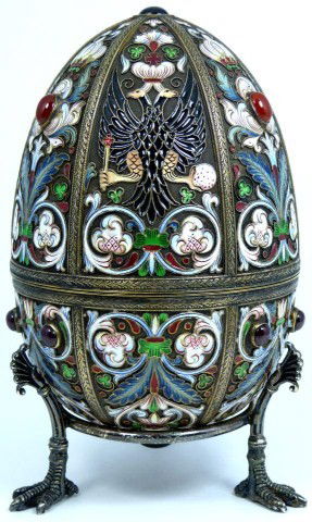 RUSSIAN SILVER & ENAMEL JEWELED DOUBLE EAGLE EGG: Finely crafted Russian silver egg with multicolor enameled design throughout depicting scrolled flowers and double headed eagle crests. Has 7 set Cabochon garnets and 3 red coral stones to exterior. H