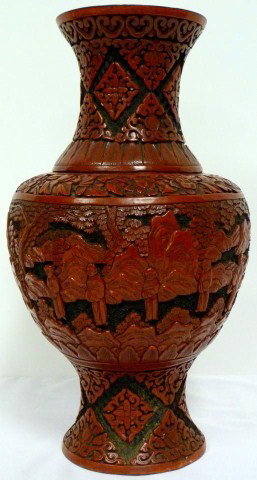 ANTIQUE CHINESE CINNABAR VASE: Beautifully carved red and black cinnabar vase. Depicts relief scenes of men standing with trees and rocks visible in the background. No apparent signature. 19th century. Measures 14 1/4" heigth (36.1