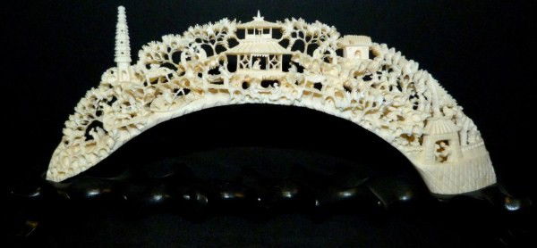 CHINESE RELIEF CARVED IVORY TUSK VILLAGE SCENE: Fully reticulated hand carved village scene depicts pagoda, people, animals and trees. Measures 4 1/2" height + 1 3/8" base (11.4cm x 3.4cm). 19th century.