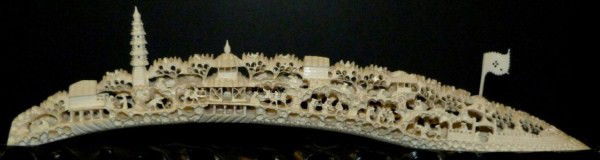CHINESE CARVED TUSK w RETICULATED VILLAGE SCENE: Fully reticulated hand carved Chinese ivory village scene. Depicts villagers, trees, pagodas, people and walls. Measures 4 1/2" height x 18 3/8" length (11.4cm x 46.6cm). 19th century.