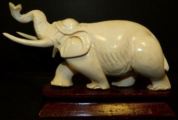 CHINESE IVORY HAND CARVED ELEPHANT FIGURE: Chinese ivory hand carved figure depicting an elephant with trunk up. Set on wooden base. 19th/20th century. Measures 3 1/4" height x 6 1/4" length + 7/8" base (8.2cm x 15.8cm + 2.2cm).