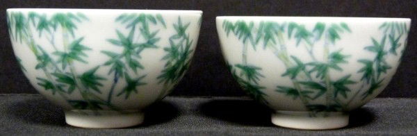 PAIR OF YUNG CHENG PORCELAIN ENAMELED TEA CUPS: Exquisite pair of cups with enameled bamboo design to sides. Yung Cheng reign marks to bottom (1723-1735). Includes fitted wooden box. Measures 1 1/2" height x 2 5/8" diameter (3.8cm x 6.6cm).