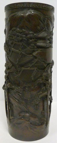 ANTIQUE CHINESE BRONZE CYLINDRICAL VASE: Bronze cylindrical vase depicting a village scene with raised design. Etruscan pattern to rim. 19th/20th century.