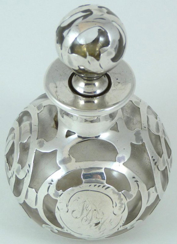 ANTIQUE GLASS PERFUME BOTTLE w FINE SILVER OVERLAY: Antique perfume bottle with stopper. Has scrolled 999/1000 fine silver overlay. Silver overlay is marked by the Alvin Silver company. Bottom of bottle is marked "669". Circa 1900. Measures 3 3/8" heig