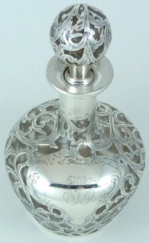 ANTIQUE GLASS DECANTER w ALVIN FINE SILVER OVERLAY: Antique glass decanter with stopper. Has scrolled 999/1000 fine silver overlay. Has monogram. Silver overlay is marked by the Alvin Silver company and numbered "33". Bottom of bottle is marked "L.C."