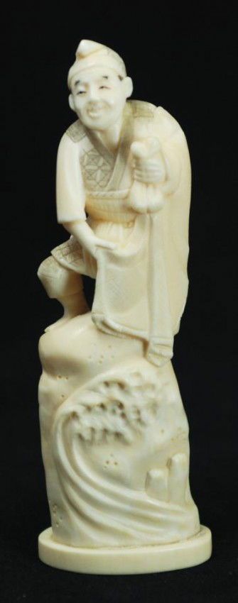 JAPANESE CARVED BONE FIGURE OF FISHERMAN: Hand carved Japanese bone figure depicting a fisherman. He is readying his net to throw into the water. He is standing on a rock and waves can be seen crashing into it. 19th century. Signed to bottom.