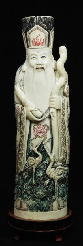 CHINESE CARVED IVORY FIGURE OF WISEMAN: Hand carved Japanese ivory figure depicting a man with wooden staff. In his right hand is a Scroll. He is wearing layered robe and head dress with intricate polychromed flowers, bamboo, patterns, call