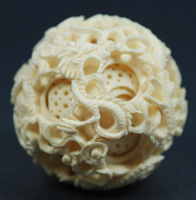 CARVED IVORY 9 LAYER DRAGON CONCENTRIC BALL: Carved Chinese ivory 9 layer dragon concentric ball. Has 9 concentric carved balls. Outer layer has a relief carved dragons and clouds design. Measures 2 1/2" diameter (6.4cm).